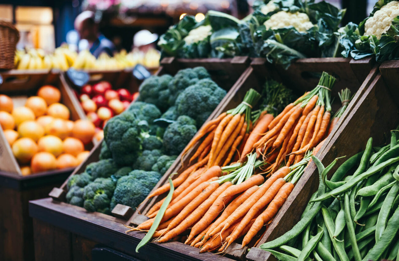 Fresh vegetables in wooden crates, on sale at a market stall.